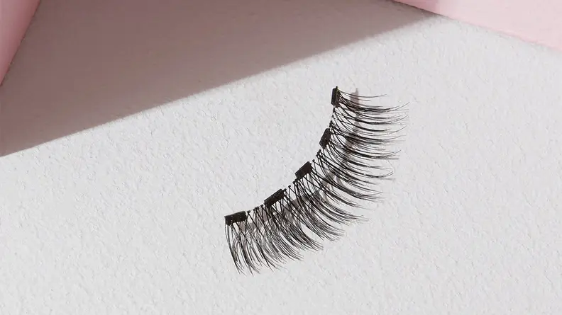 A single magnetic eyelash from the Lola’s Lashes Rose Quartz Magnetic Eyelashes and Eyeliner Kit on a white background.