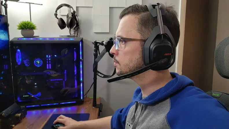 A man wearing a pair of Logitech Astro A50 X headphones while gaming on his PC.