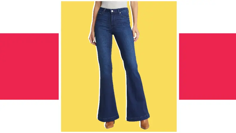A model wears a pair of flared blue denim jeans.