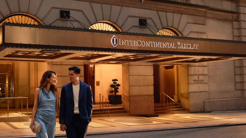 The front of a historic hotel with a couple walking