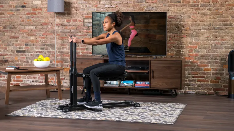Woman using DB method squat machine at home.