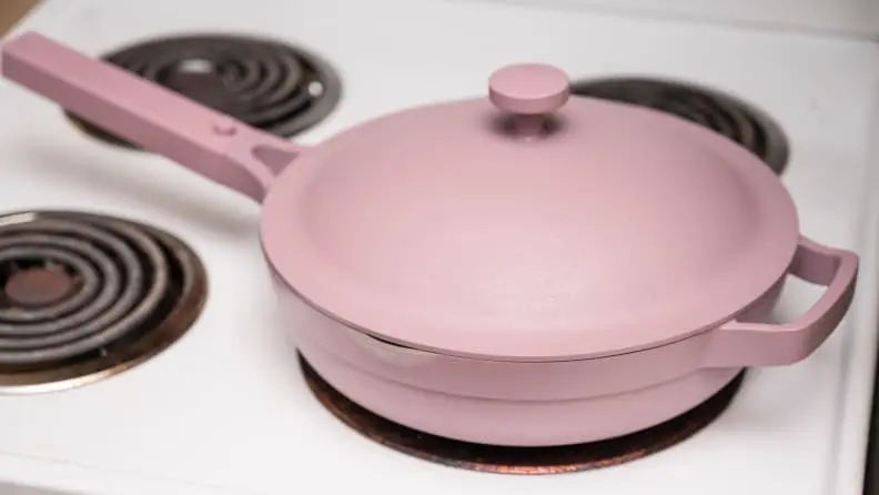A lavender colored Always pan is on a white stove.