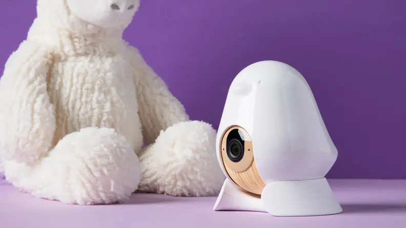 Cubo Ai Plus Smart Baby Monitor on a purple background with a stuffy.