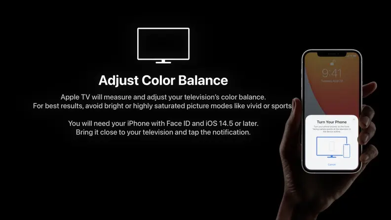 A person holds an iPhone to change the color correction on a darkened television.