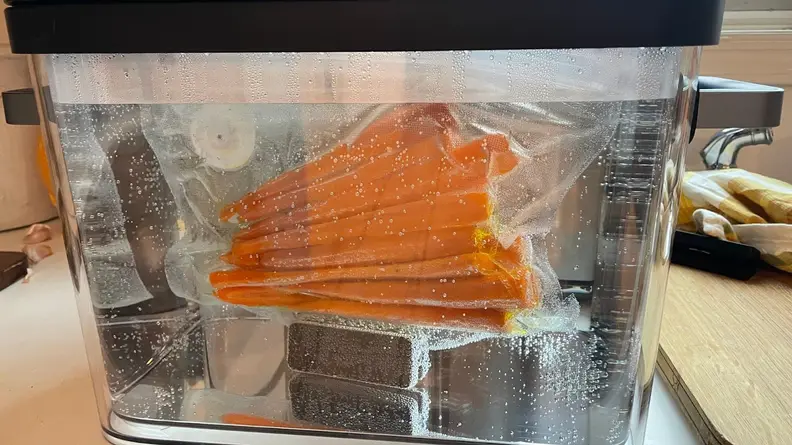 Vacuum sealed bag of carrots submerged in water.