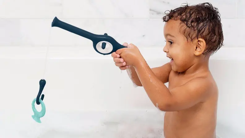 A young Black child plays with a fishing rod toy.