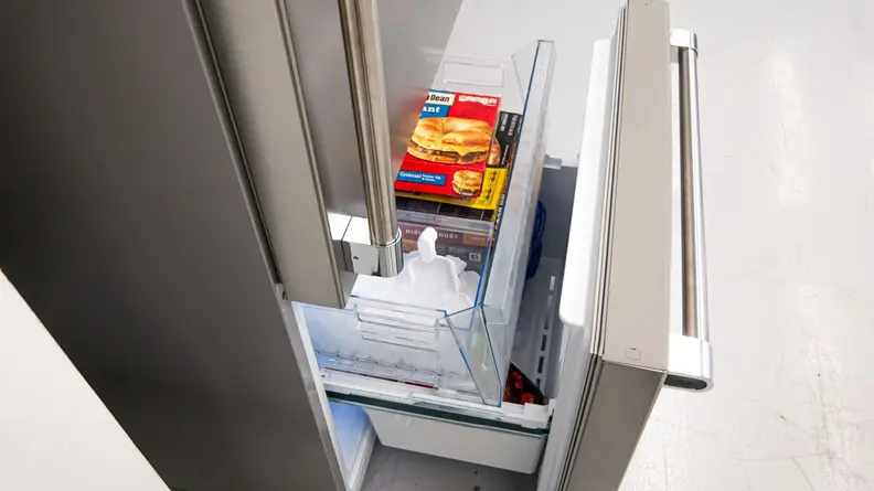 Freezer drawer pulled out on the Beko BFBD30216SSIM Bottom-freezer Refrigerator displaying ice and frozen breakfast sandwiches.
