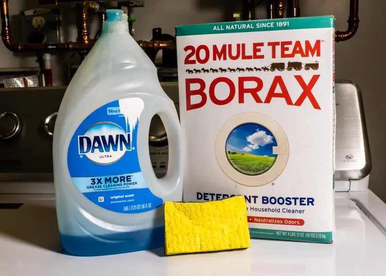 A bottle of Dawn dish soap, a box of Borax, and a yellow sponge sit on top of a washing machine.