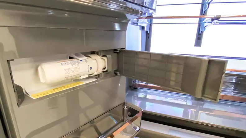The Café CVE28DM5NBS5 French door refrigerator's water filter compartment, open, showing the filter in place.