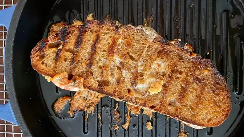 A grilled cheese cooks on a cast-iron grill pan.