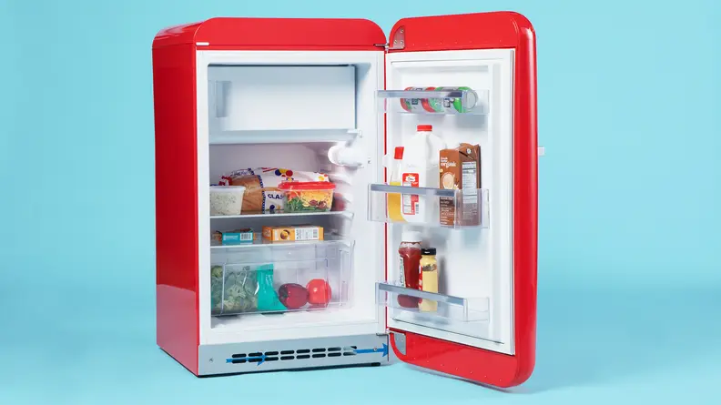 A close up of the Smeg FAB10URRD3 mini fridge. Its door is open, showcasing a fully-stocked interior.