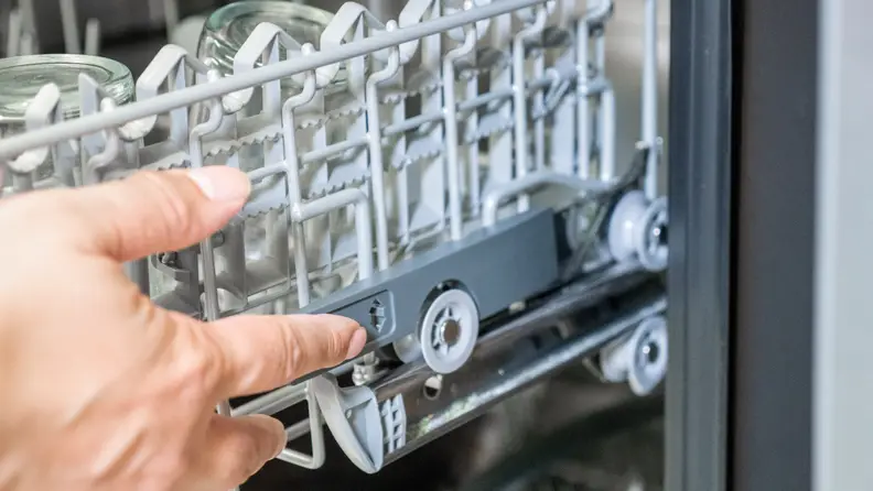 A hand reaches into frame to adjust the height of the upper rack.