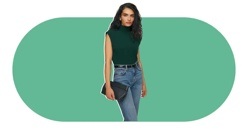A model wearing a green mock neck cashmere sweater that doesn’t have sleeves.