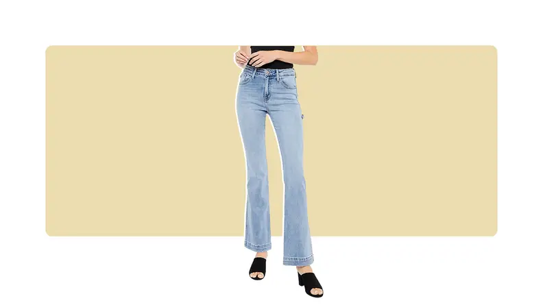 A model wearing light-wash bootcut jeans with black slip on shoes.