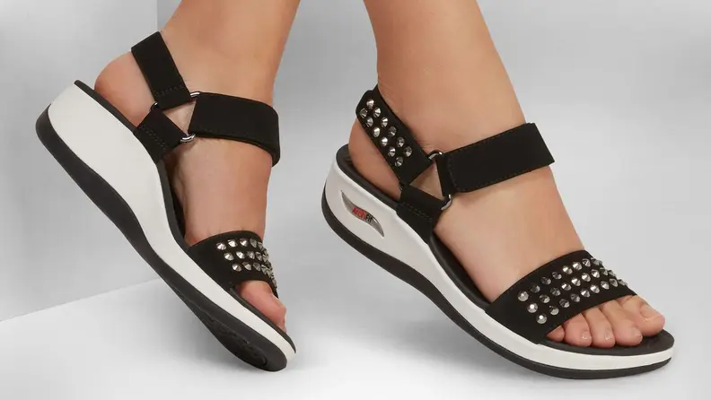 Woman wearing black sandals with legs crossed.