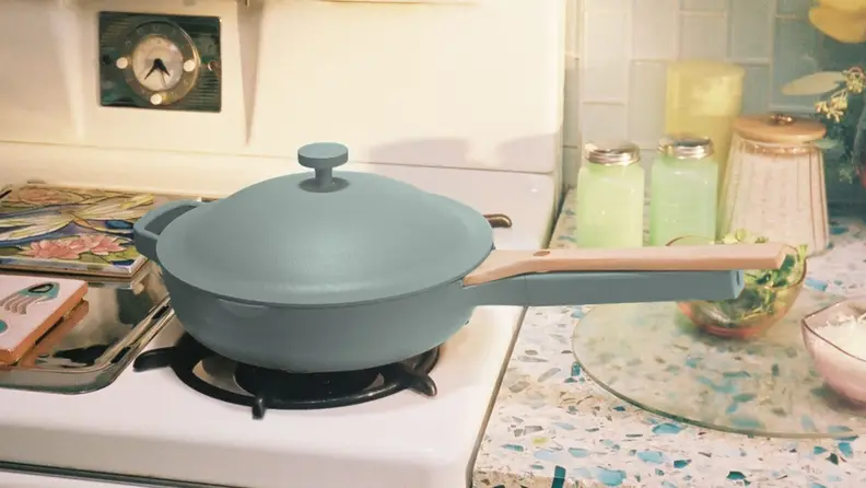 A light blue pan with a lid sits on a gas stovetop in a modern kitchen.