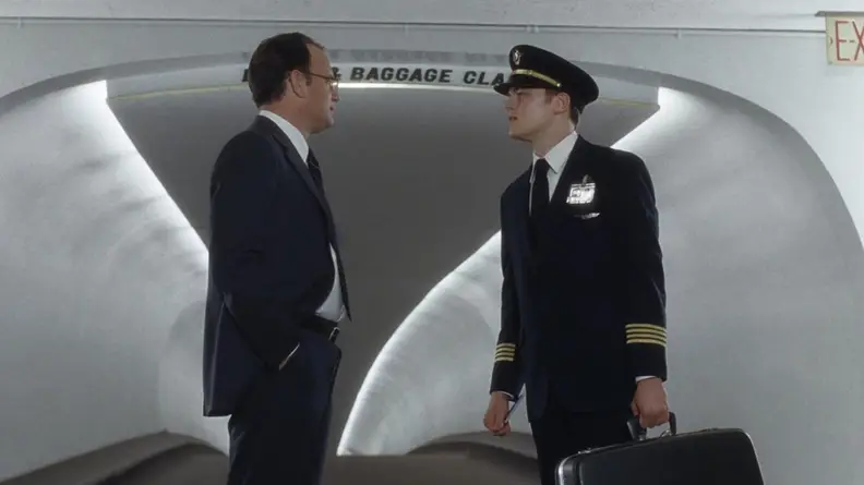 Frank (Leonardo DiCaprio) dressed as an airline pilot talking with Carl (Tom Hanks).