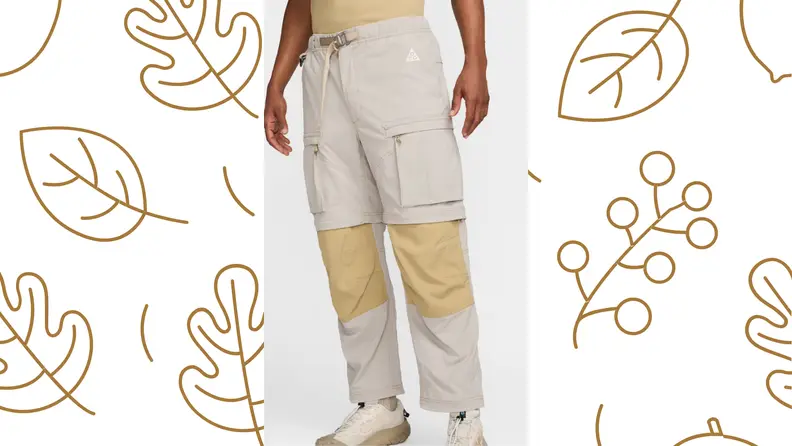 A person stands in a pair of pants from the waist down, over a leaf-printed background