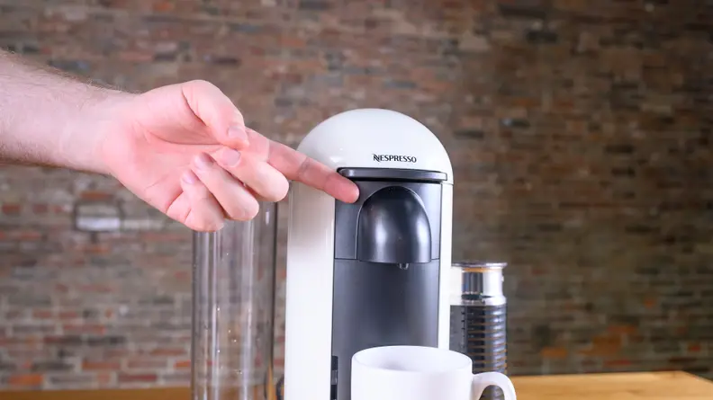 Finger pointing at Nespresso VertuoPlus by Breville single-serve coffee maker
