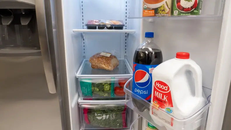 A close-up of the Frigidaire FFSS2315TS side-by-side refrigerator's three crisper drawers, filled with food for scale.