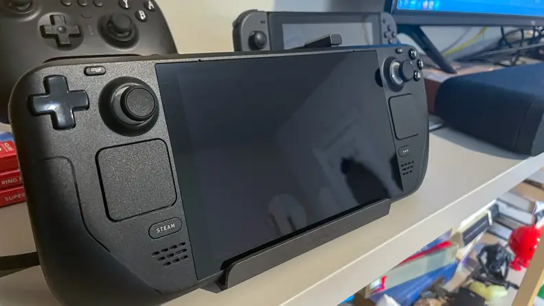 The Steam Deck placed on a dock on a shelf alongside other consoles like the Nintendo Switch.