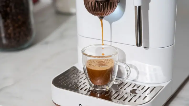 Close-up of Affetto machine pouring crema-topped espresso into a glass shot mug.