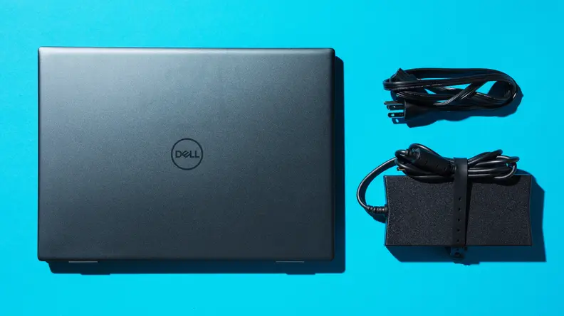 The Dell Inspiron 14 Plus on a blue background with cords wrapped up next to the laptop.