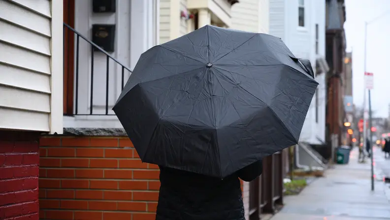 Person holding the Totes Titan Neverwet Umbrella in the rain.
