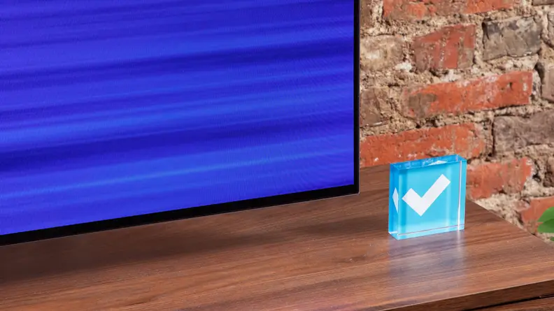 Close-up of the corner of the LG C3 OLED TV with an adjacent Reviewed logo checkmark cube.