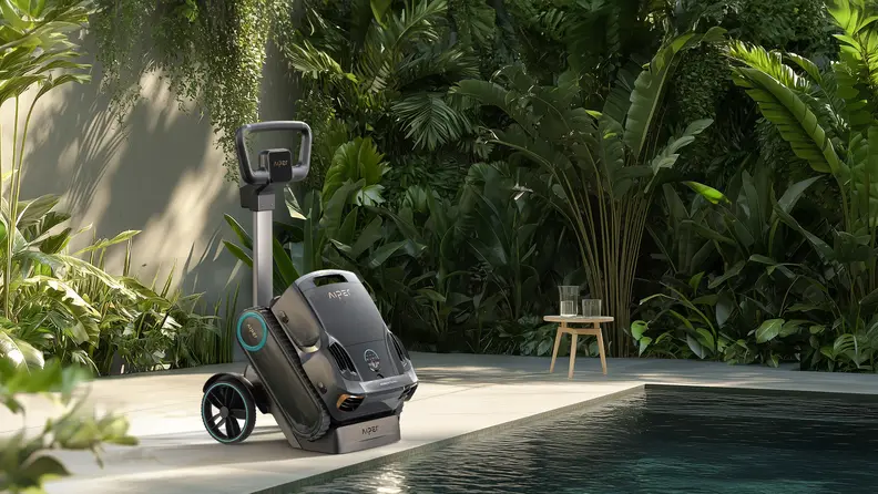 A pool robot vacuum sitting in a caddy outside by the edge of a green pool