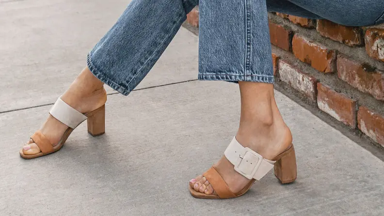 Woman on sidewalk wearing white Chinese Laundry heeled sandals.