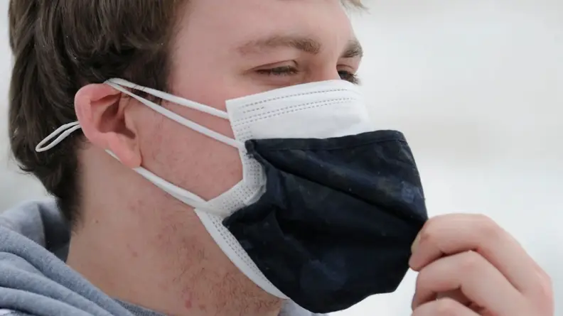 Close-up: An individual wears two cloth masks for extra protection against airborne diseases.