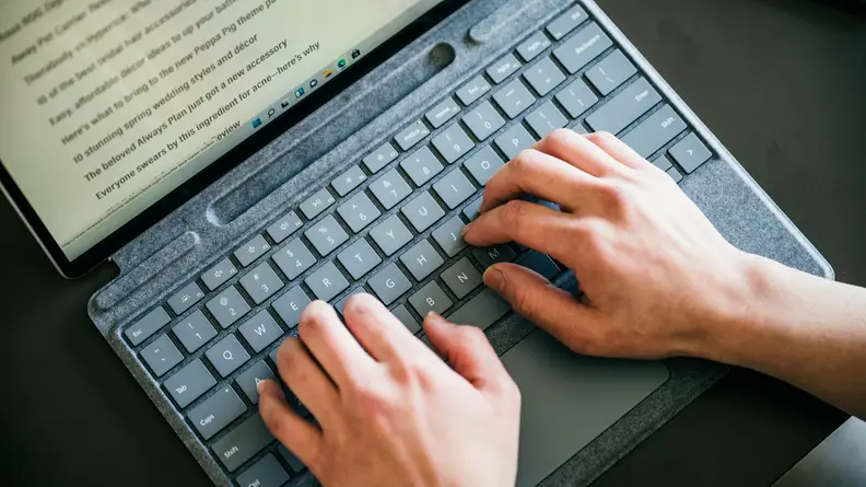 A close-up of the Surface Pro 8's Type Cover, with hands over it, about to type.