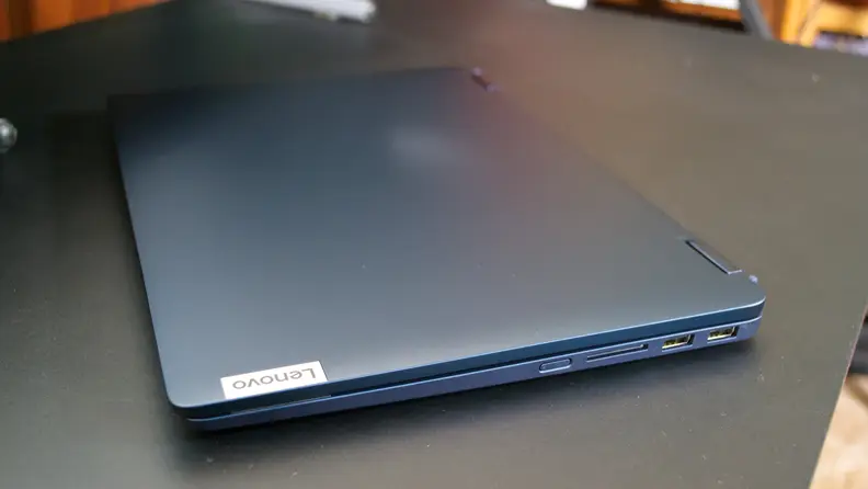 Navy blue Lenovo IdeaPad Flex 5i 14 folded in half on top of black desk surface indoors.