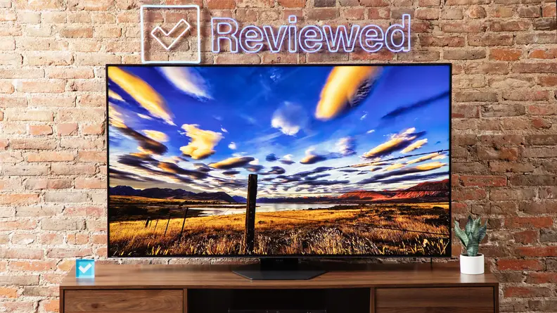 The Hisense U8N displaying a colorful, blue and orange sky in a living room setting in front of a brick wall.