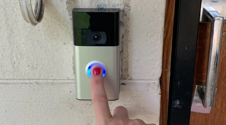 Finger with red nail polish pressing button of Ring Doorbell