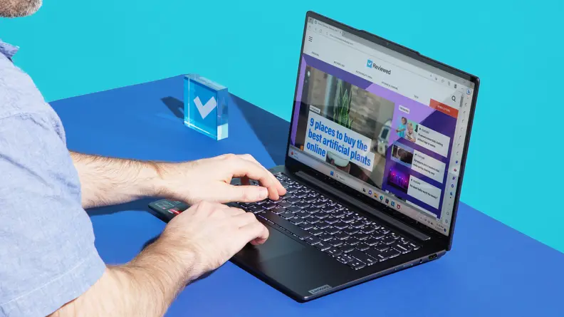 A person typing on a laptop against a blue background.
