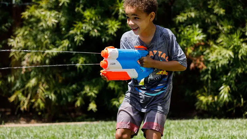A boy shoots water from a Nerf Twin Shot Super Soaker