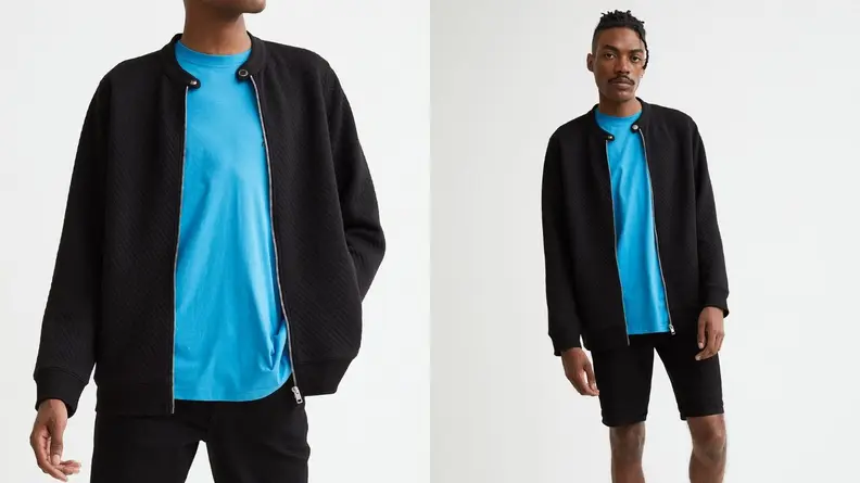 Man wearing a black zippered cardigan over a blue t-shirt, man modeling a black cardigan over a blue shirt.