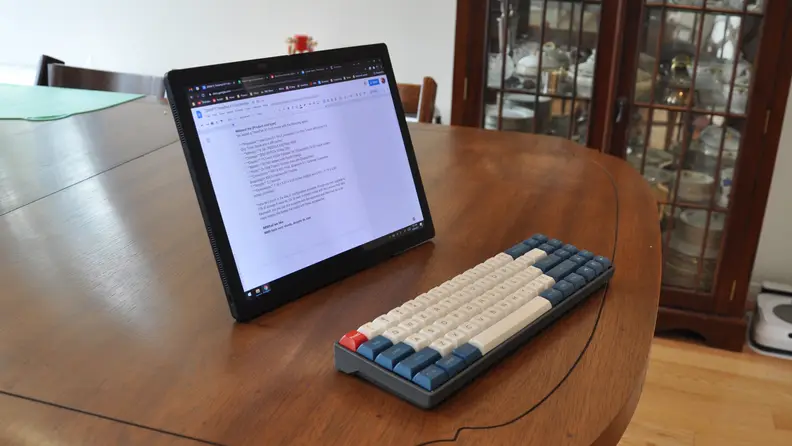 The single piece Fold sits on a wooden table in front of a multi-colored mechanical keyboard.
