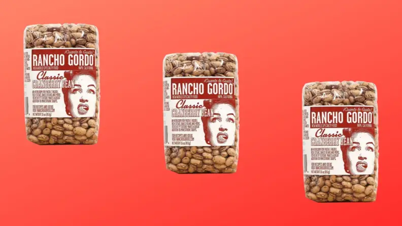 Three packages of cranberry beans arranged in a diagonal row on a red background.