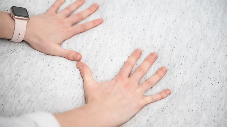 Pair of hands pressing down on a mattress