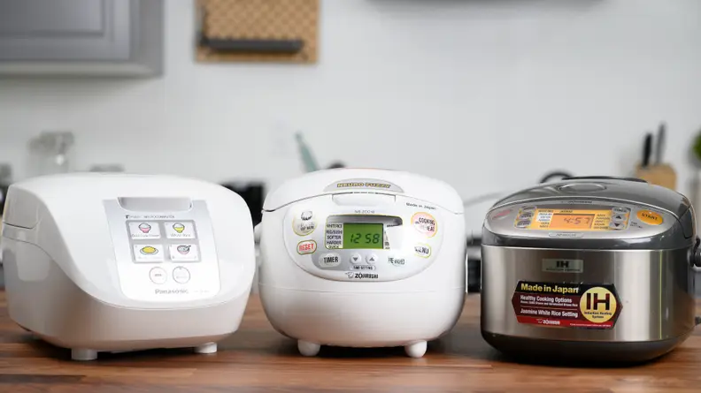 Three rice cookers sitting on a table.