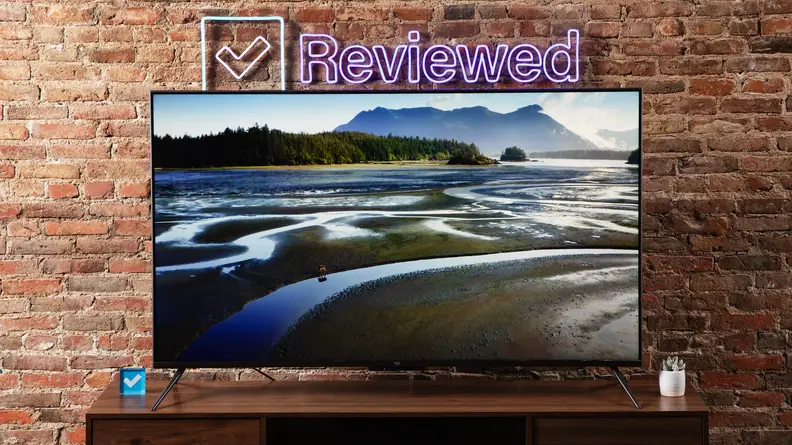 The Amazon Fire TV Omni on a wooden table displaying an outdoor scene of wetlands with mountains in the background.