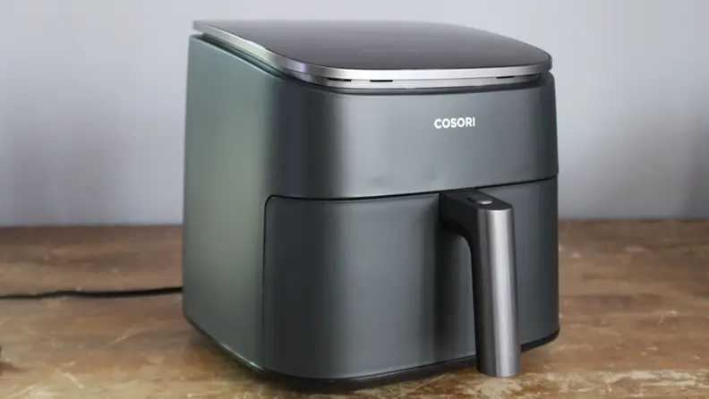 The Cosori TurboBlaze on a counter with a plate of crispy roasted potatoes.