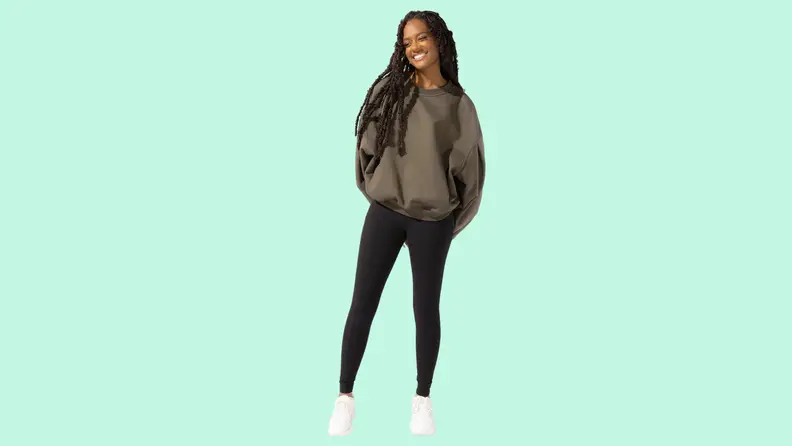 A model wearing a gray sweatshirt and black tights.