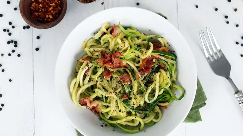 A bowl of zucchini noodles in a white bowl, shot from above