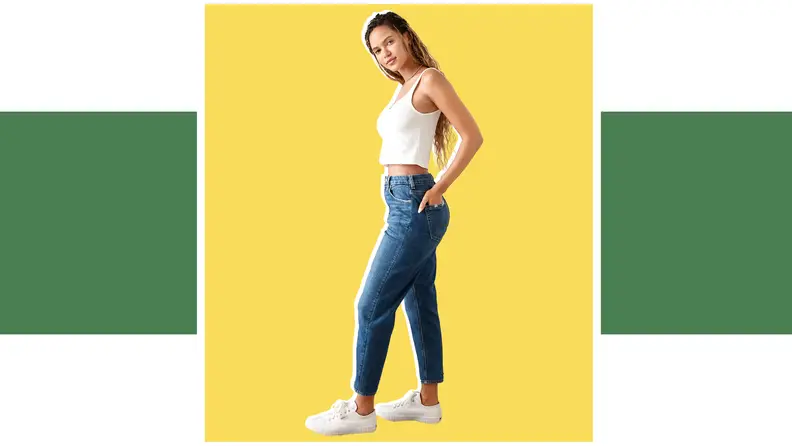 A model poses wearing a white tank top and blue jeans.