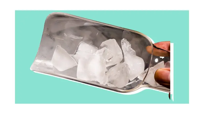 Person holding several pieces of ice with metal ice scoop.