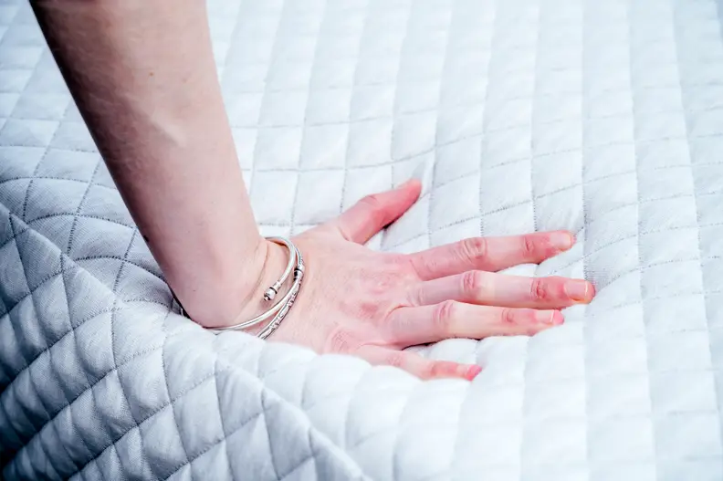 a hand presses into the surface of the Leesa hybrid mattress